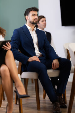 Attentive business specialists listening to lecture during corporate course in modern educational environment