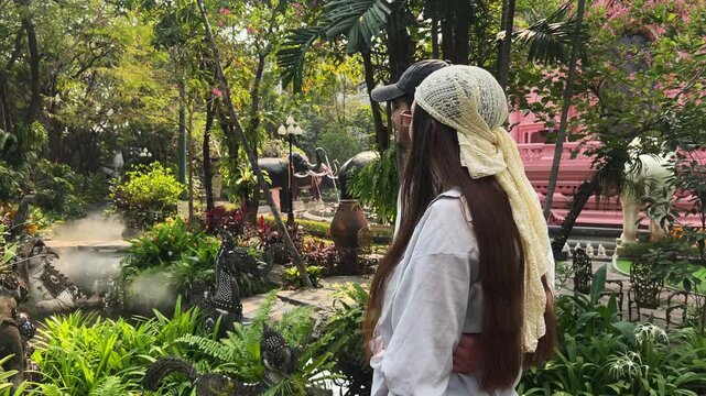 couple strolls through botanical park, they kiss and enjoy nature of tropics. Tourist activity, visits to cultural attractions and day trips correspond to concept of recreation and discovery.