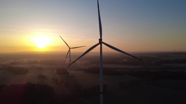 Aerial view of wind turbines in an open field during a beautiful golden sunset