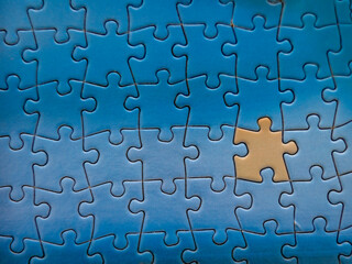 Close up of blue puzzle pieces put together with one in brown that looks like a person