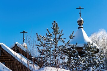 Obraz premium Winter beauty: snow-laden Russian Orthodox church domes and crosses rise against a vibrant blue sky. A peaceful, spiritual scene amidst frosty pines, Russia