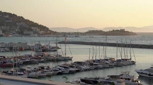  Panoramic sunset view of the crowded Kusadasi marina with luxury yachts and cityscape in the background, Kusadasi, Aydın, Turkey