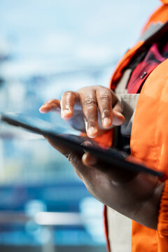 Close up of offshore platform worker managing maintenance systems with tablet, scheduling equipment repairs. Employee overseeing mechanical and structural integrity of drilling rig