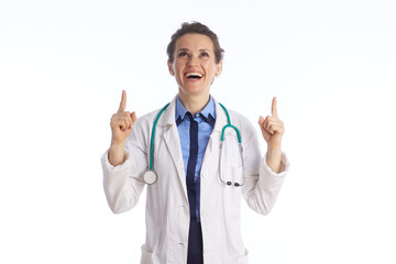 An enthusiastic female physician points up with both hands while looking upward, suggesting a breakthrough, a positive announcement, or a feeling of medical achievement.