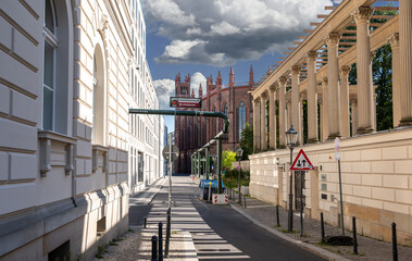 Berlin, Germany, August 11, 2023. Friedrichswerder Church, a historic neo-Gothic building, seen along a city street, with a classical colonnade. Green pipes from the city's water supply.