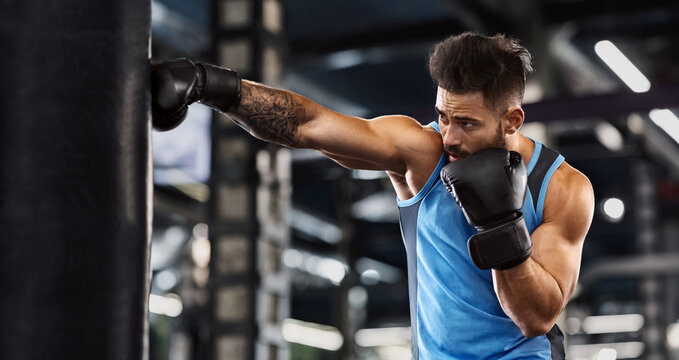 Young sportsman boxing workout at gym, guy punching boxing bag, free space