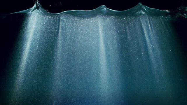 Dark Blue Ocean Surface Seen from Underwater , Super Slow Motion . Abstract Waves and Rays of Sunlight Shining Through