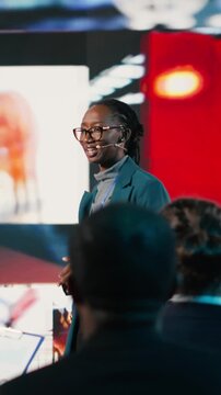Vertical Video Black young adult presenter during a social media presentation at business summit. Speaker sharing digital marketing strategy, branding and communication insights at event focused on