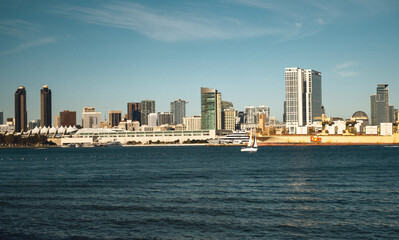 Fototapeta premium Picturesque Harbor City Under Sunny Sky. Cityscape Along Coast With Vessels And Bright Reflections