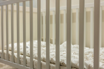 Fototapeta premium Baby crib with soft bedding closeup. Gentle safety.