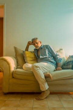Stylish mature man with silver hair relaxing on a sofa in a bright living room
