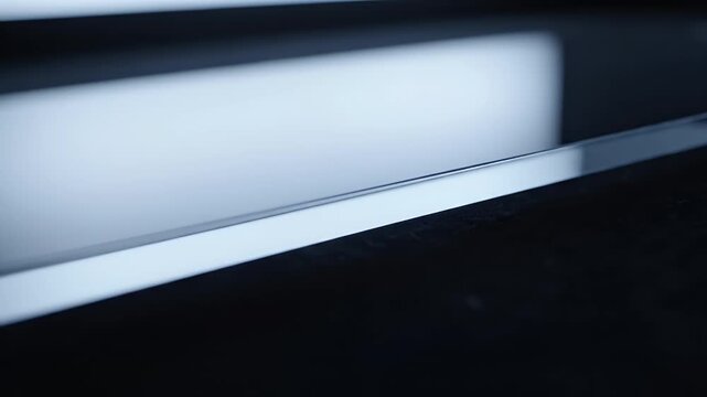 Close-up of a beveled transparent glass edge under cool blue backlighting on a dark surface