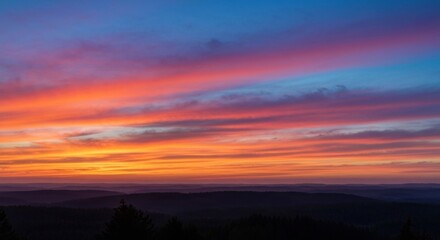 Fototapeta premium Vivid sunset with streaks of color above silhouetted hills and trees