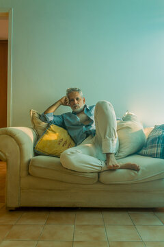 Stylish mature man with silver hair relaxing on a sofa in a bright living room