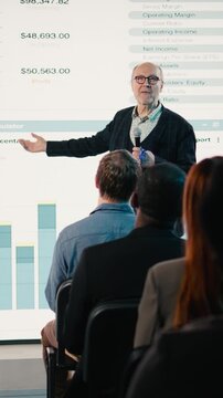 Vertical Video Senior businessman starting a business conference presentation and taking the stage with applause, professional speaker addressing diverse audience. Corporate event in conference hall