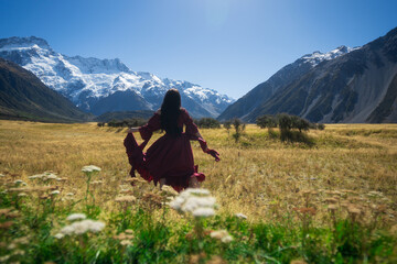 Woman in field overlooking alps in long dress
