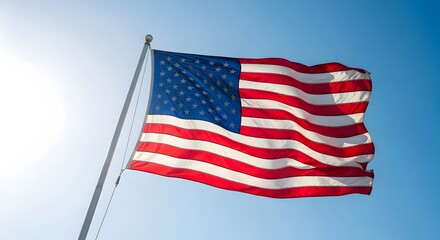 Obraz premium American Flag Waving Proudly Against Bright Blue Sky - Symbol of USA Patriotism and Freedom