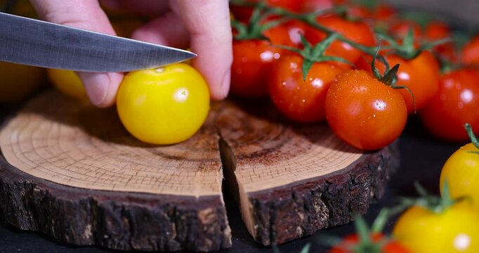 a yellow tomato cut into half and wet round fresh and sweet tomatoes of red and yellow color, yellow tomatoes with dots on the peel, one yellow tomato is divided into half