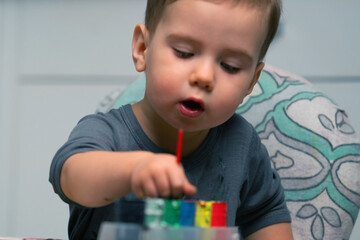 Documentary style candid photo of toddler with painted hands, authentic childhood emotions, everyday family life.