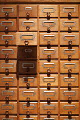Wooden cabinet with many drawers showing an organized storage system in a library or archive