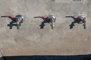Water taps on a rough concrete wall in a rural area during drought