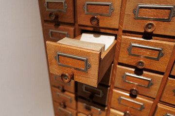 Vintage wooden card catalog with open drawer and visible index cards in a library or archive setting