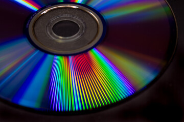 Fototapeta premium Vibrant closeup of a CD surface displaying colorful rainbow light reflections and diffraction patterns, abstract technology background with vivid spectrum lines on a dark backdrop.