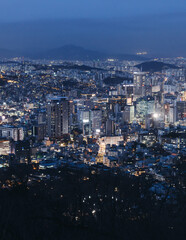 Naklejka premium Seoul night skyline, South Korea, beautiful aerial twilight view, with mountains and scenery beyond the city, seen from observation deck of Namsan Park, Gyeonggi-do province, Republic of Korea