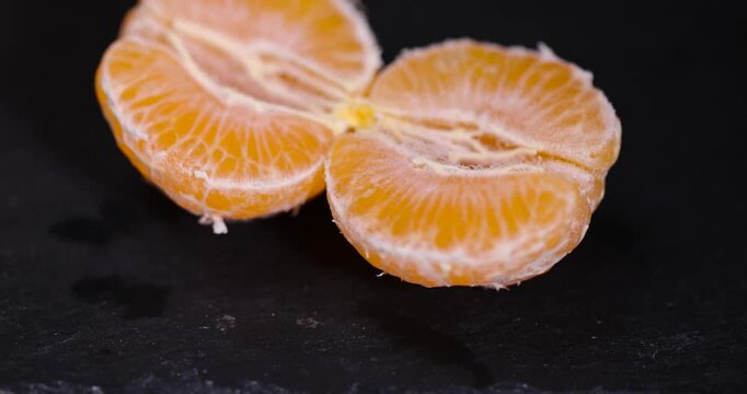 sliced juicy peeled orange tangerine on a slate table, ripe orange small mandarin without peel on a black slate board, tangerine divided into small slices