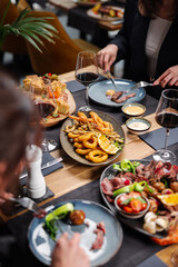 Sharing dishes during a group dinner at a restaurant table
Restaurant table spread with steaks, seafood and shared plates
Friends sharing a variety of dishes during a cozy dinner
