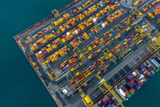 Aerial view of brightly colored shipping containers stacked in neat rows on the docks, a symphony of commerce and industry, Trieste, Italy.