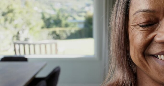 Woman moving into frame, widening smile, laughing, turning to offscreen voice by table, copy space
