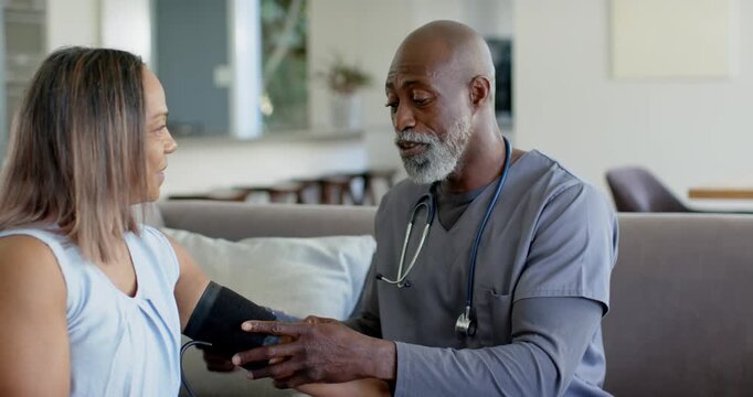 Clinician in scrubs with stethoscope doing home BP check, managing cuff and explaining to woman