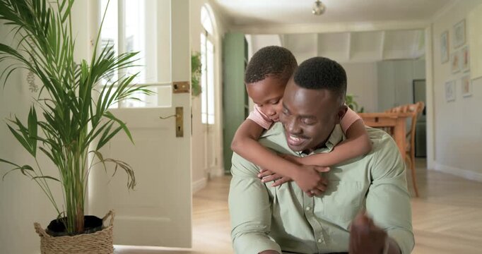 African American father and son sitting on step, child hopping onto back, sharing smartphone view