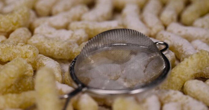 yellow large sticks of corn flour with added sugar for quick cooking with milk or yogurt and powdered sugar, ready-to-eat corn sticks scattered on food paper along with powdered sugar