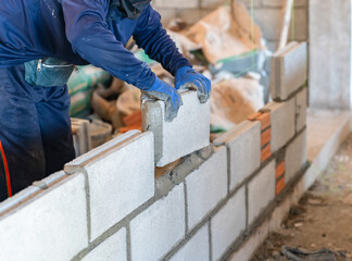 Close up of construction worker building a concrete block wall with mortar