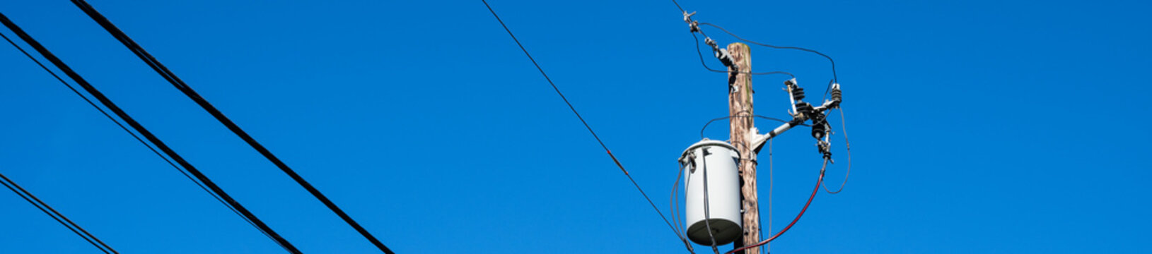 
Top of wood utility pole with transformer, lightning arrestor, and fuse disconnect, part of the electrical power distribution system
