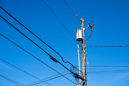 Top of wood utility pole with transformer, lightning arrestor, and fuse disconnect, part of the electrical power distribution system, with new fiberoptic cable installation below

