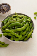 Edamame pods with salt and pepper and a dipping sauce, healthy protein snack