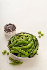 Edamame pods with salt and pepper and a dipping sauce, healthy protein snack