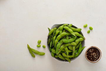 Edamame pods with salt and pepper and a dipping sauce, healthy protein snack