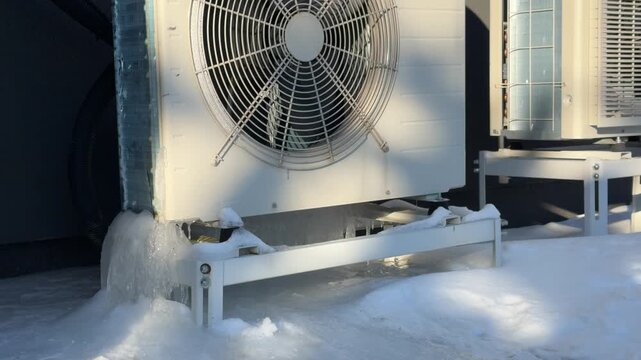 Massive Ice Buildup on Heat Pump Base. A static shot reveals a large block of ice encasing the base support of a heat pump, showing the effects of winter condensation freezing.