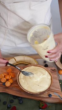 Pouring Fresh Yellow Fruit Smoothie Bowl into Wooden Bowl