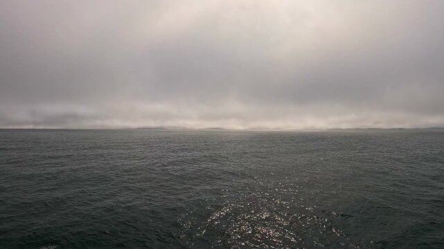 Middle of the north atlantic near the arctic circle the seas are dark, inky black with low clouds.