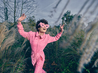 Obraz premium Playful child outdoor pink mask grass imagination nature movement sunshine, exploration and wonder in a carefree moment captured in a sunny natural setting outdoors