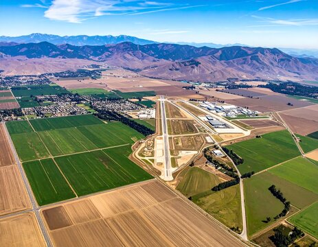 Aerial View of Agricultural Fields and Airport with Mountain Range in Background.