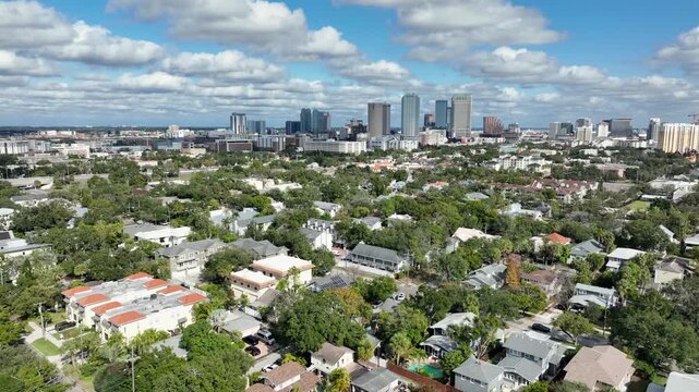 Aerial establishing shot of Tampa city skyline and upper class suburb district in summer. Wide shot. Luxury houses and architectures between green trees in neighborhood. Florida, USA.