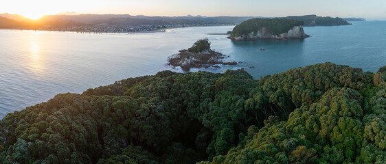 Sunrise over the town of Whangamata, New Zealand, with the sun reflecting off the water and Donut...