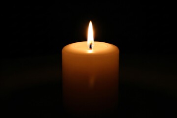 Single candle lit in darkness