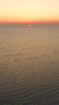 Vertical drone sunset over Provincetown sandbars, Cape Cod Bay glowing with a golden path across calm water. Tall coastal evening scene with open horizon, ideal b-roll.